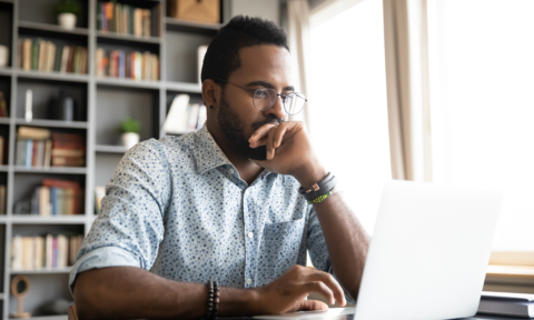 A man in glasses staring intently at a laptop screen